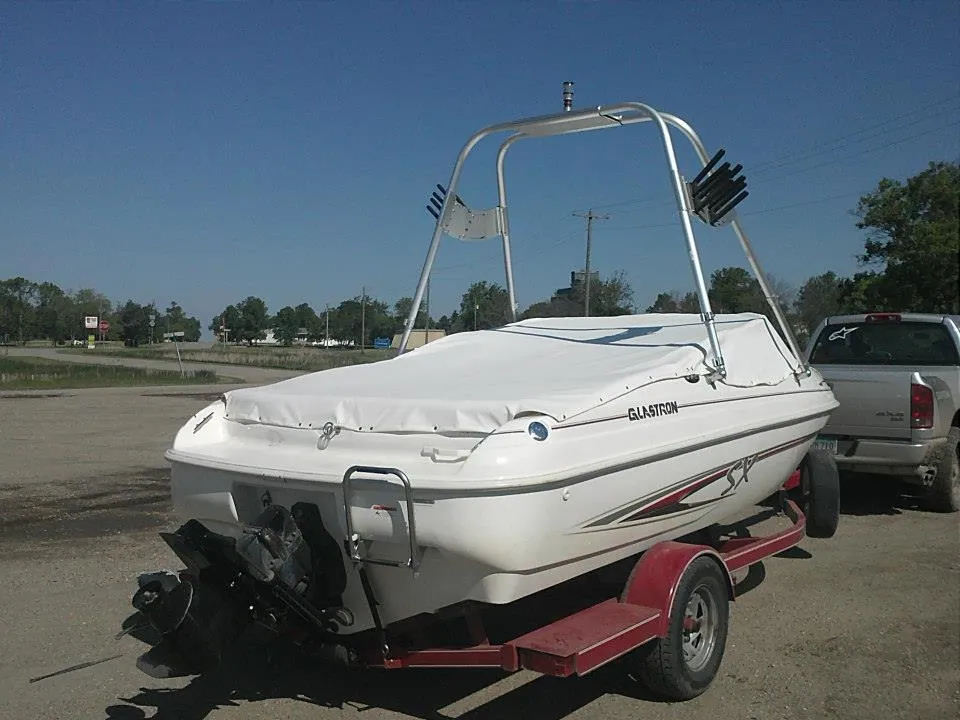Ski boat on a trailer with a white custom cover over the cockpit