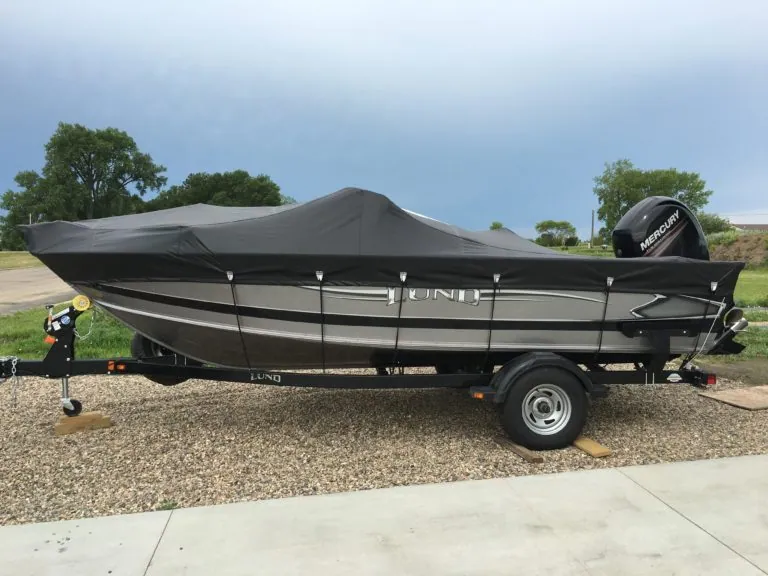 Fishing boat on a trailer under a fitted black Tarp Pro boat cover
