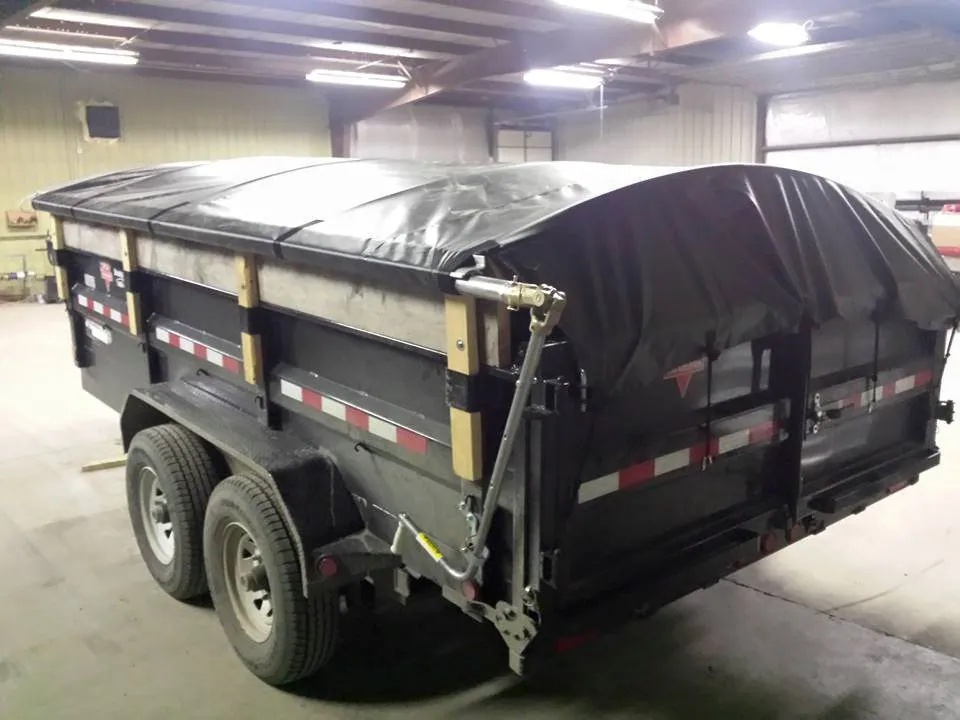 Dump trailer with a manual roll tarp pulled over the load