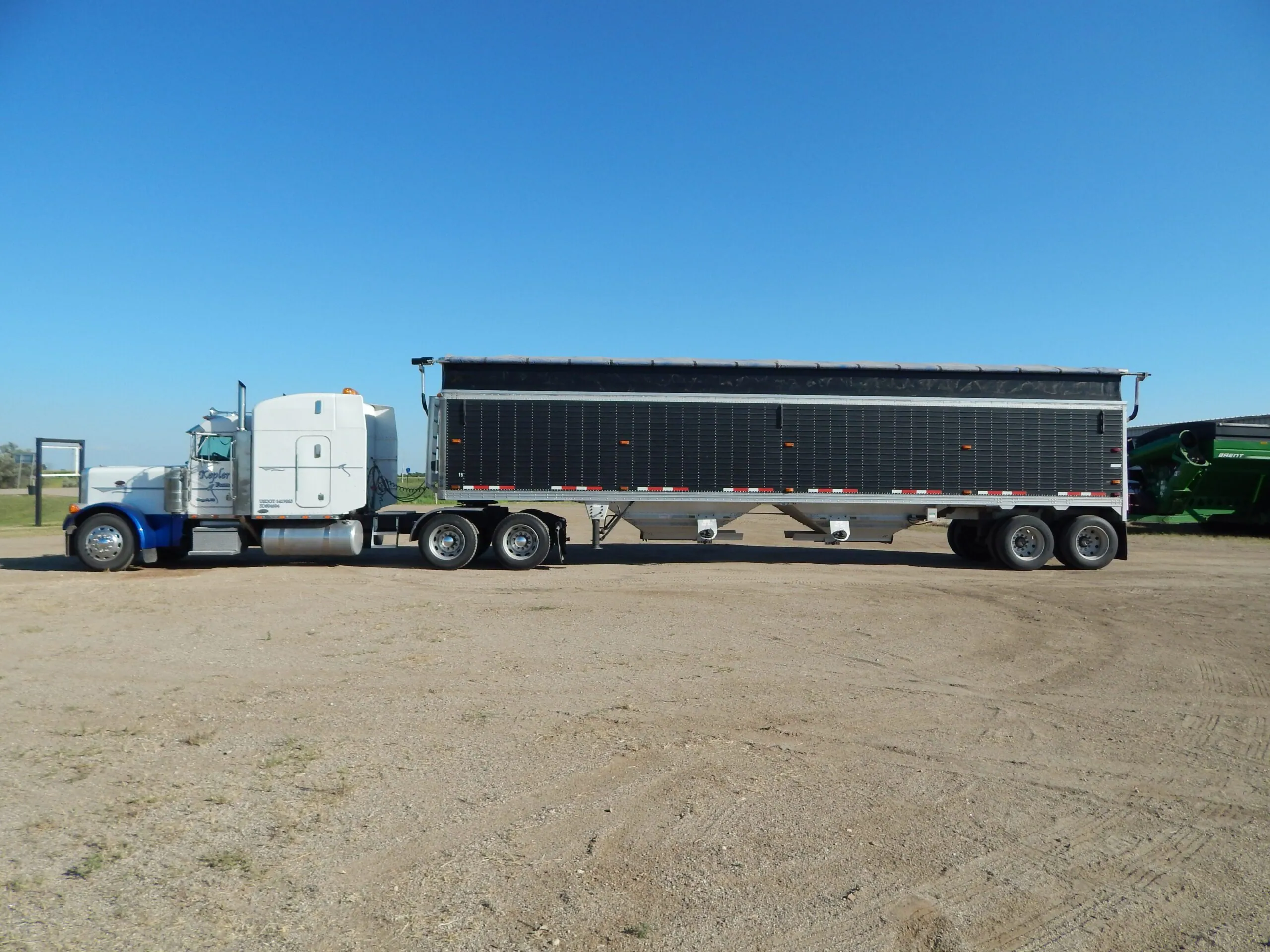 Semi truck with a hopper grain trailer fitted with a Hi-Rizer extension