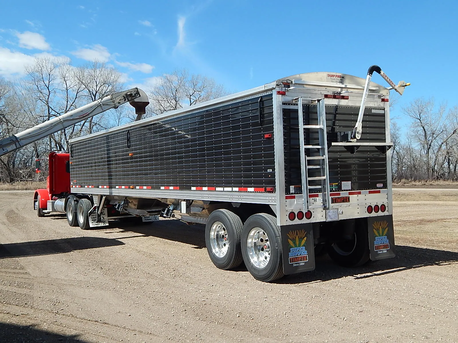 Grain trailer with an electric roll tarp kit, tarp arm raised