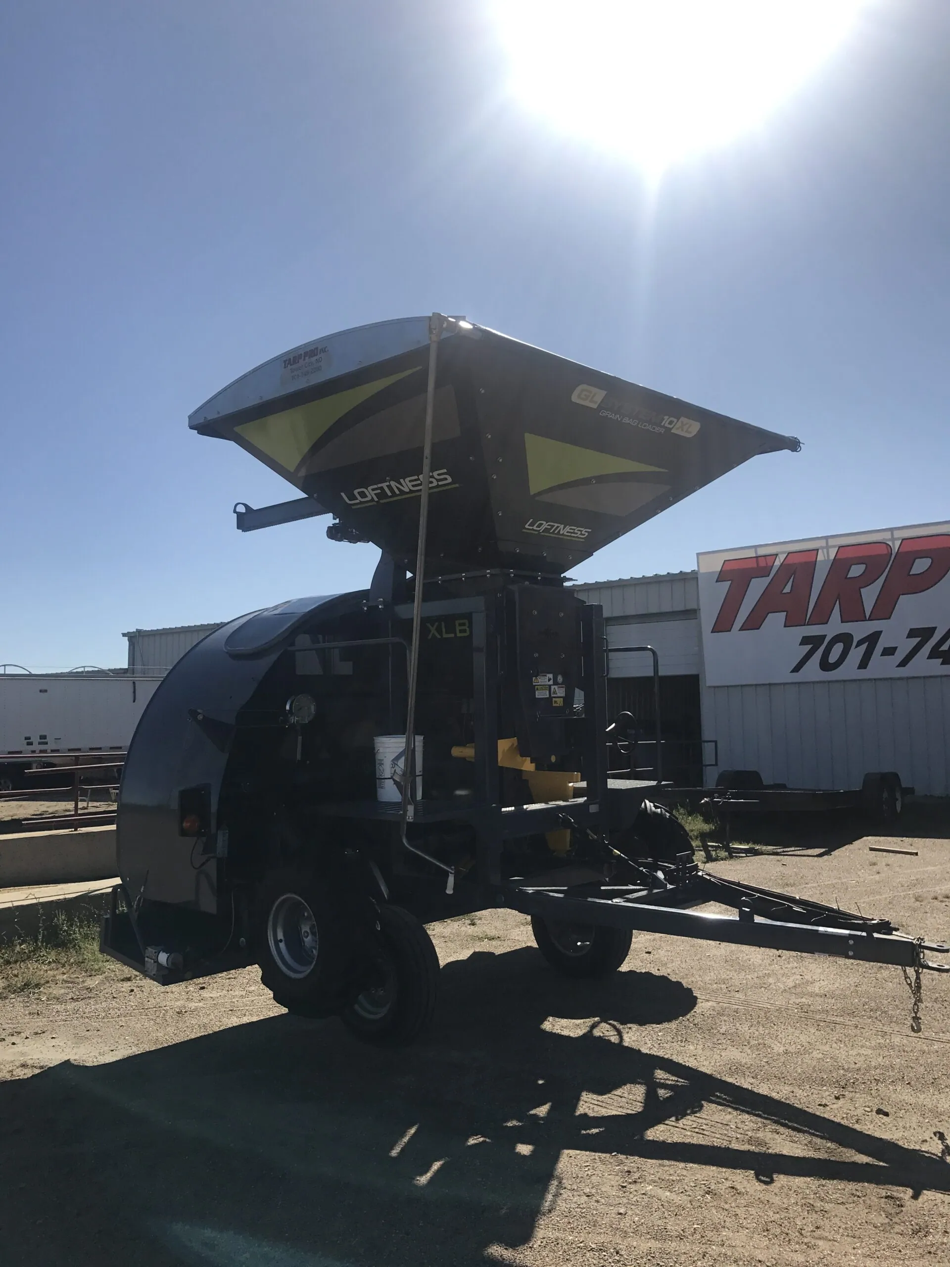 Seed tender with a roll tarp kit, arm raised, outside the Tarp Pro shop