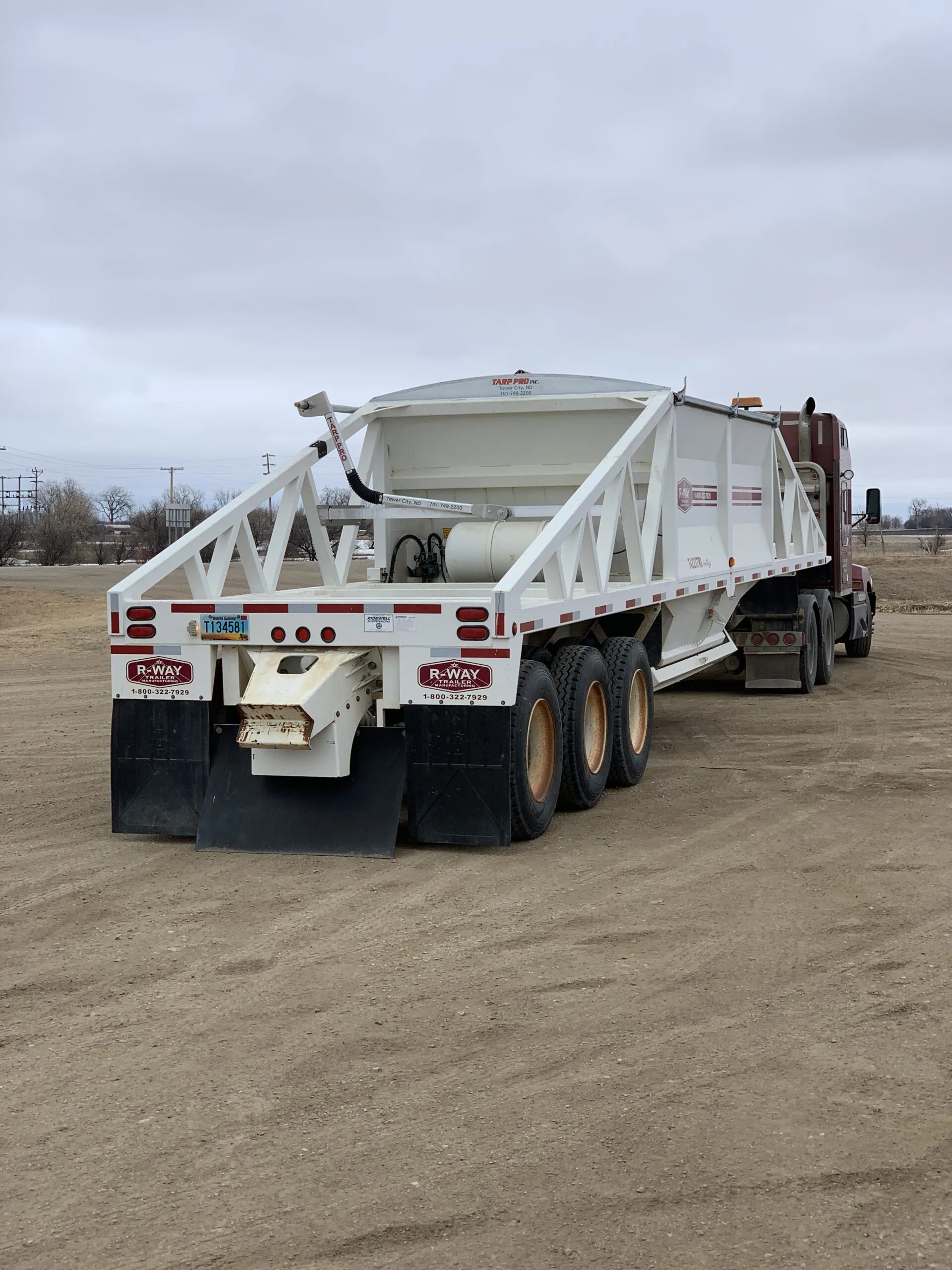 Belly dump trailer with a manual roll tarp