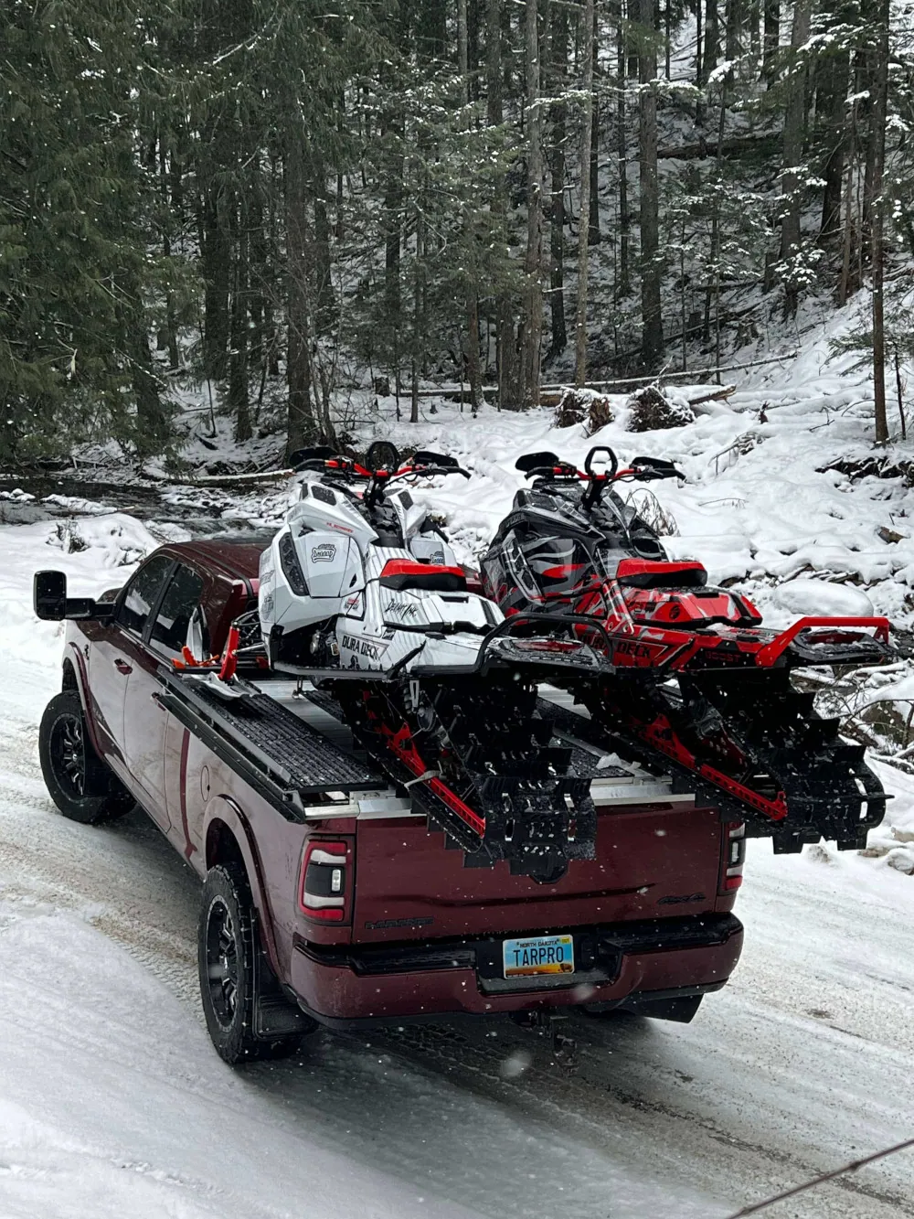 Red pickup hauling snowmobiles on a Dura Deck sled deck in the snow