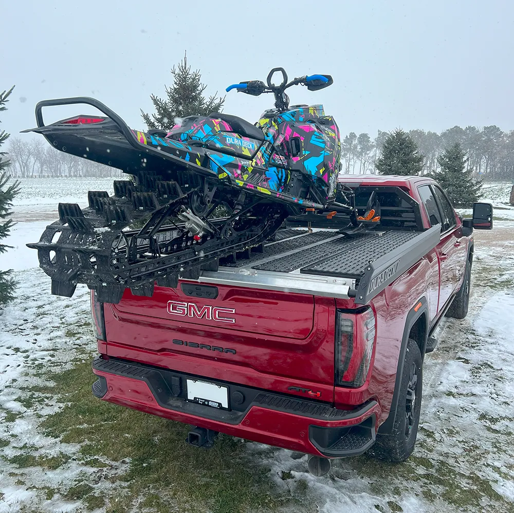 Red pickup with a Dura Deck sled deck carrying two snowmobiles